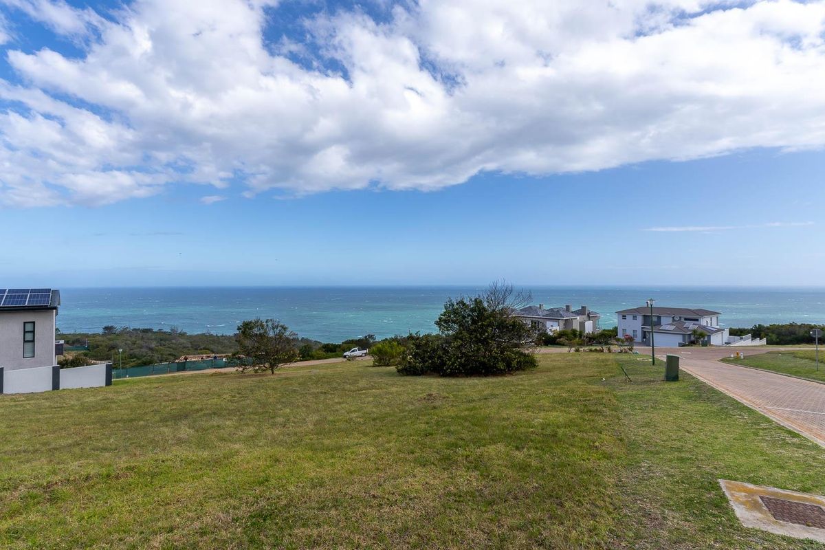 A scenic view of the coastal landscape and ocean from a vacant residential plot, featuring surrounding neighborhood infrastructure.
