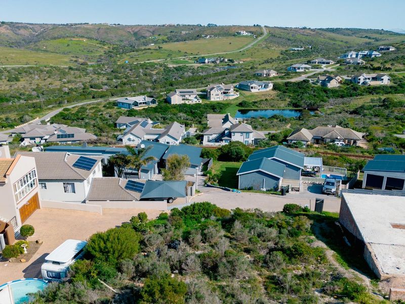 An aerial view of a residential estate featuring multiple homes, paved driveways, and surrounding natural landscape.