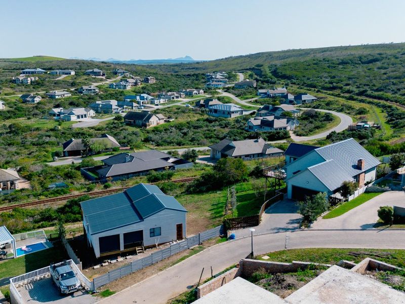 An aerial view of a residential estate featuring established homes, paved roads, and surrounding natural landscape.