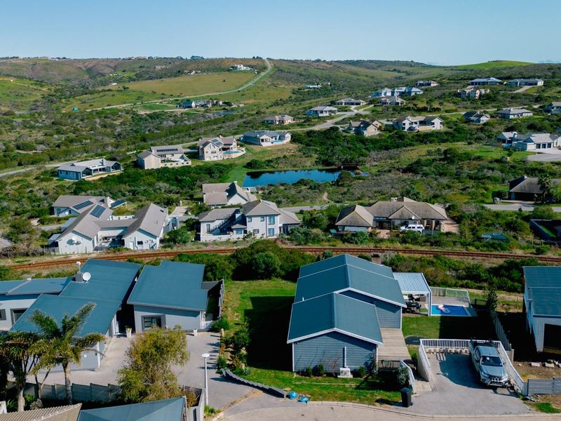 An aerial view of a residential estate featuring multiple homes, paved roads, and surrounding natural landscape.