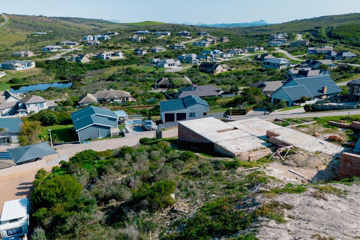 Aerial view of a residential estate featuring an active construction site with a concrete slab foundation and surrounding established homes.