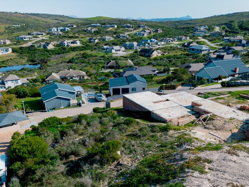 Aerial view of a residential estate featuring an active construction site with a concrete slab foundation and surrounding established homes.