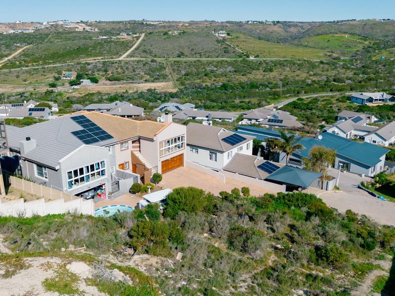 Aerial view of a residential property featuring solar panels, a swimming pool, and a paved driveway within a suburban estate setting.