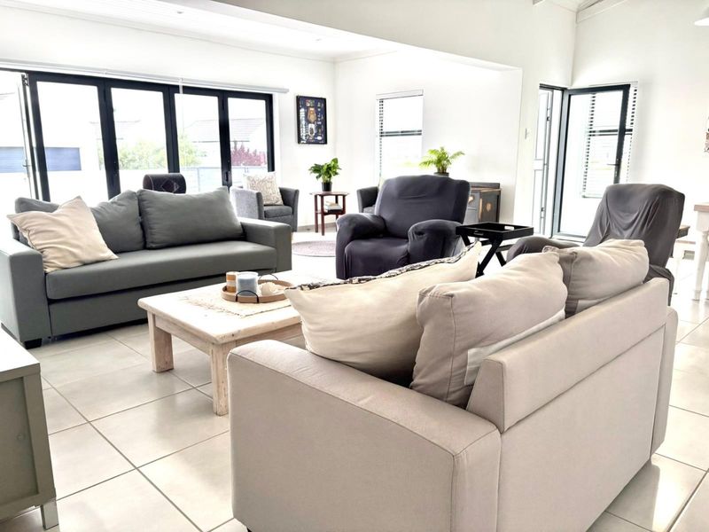 Spacious open-plan living area featuring neutral tiled flooring, modern black aluminium bifold doors, and abundant natural light.