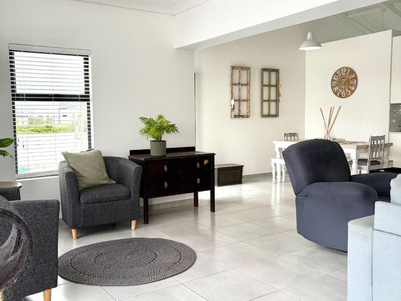 Spacious open-plan living and dining area featuring neutral tiled flooring, a white tongue and groove ceiling, and ample natural light.