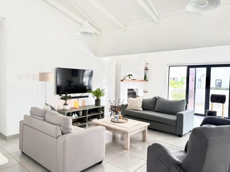 Spacious living room featuring a high vaulted ceiling, tiled flooring, a fireplace, and large sliding glass doors providing natural light and garden access.