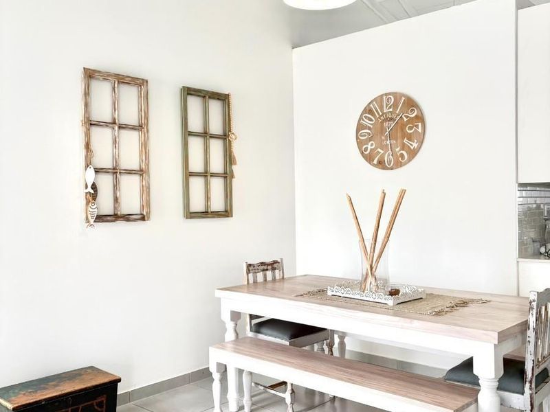 Bright dining area featuring a vaulted ceiling with exposed rafters, ceramic floor tiles, and modern pendant lighting.