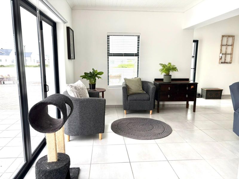 Bright living area featuring large aluminium sliding doors, neutral tiled flooring, and a clean, modern aesthetic with ample natural light.