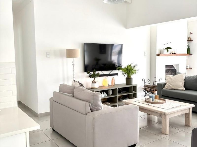 Bright and airy living room featuring a vaulted ceiling, tiled flooring, and a cozy fireplace, creating a comfortable and inviting atmosphere.