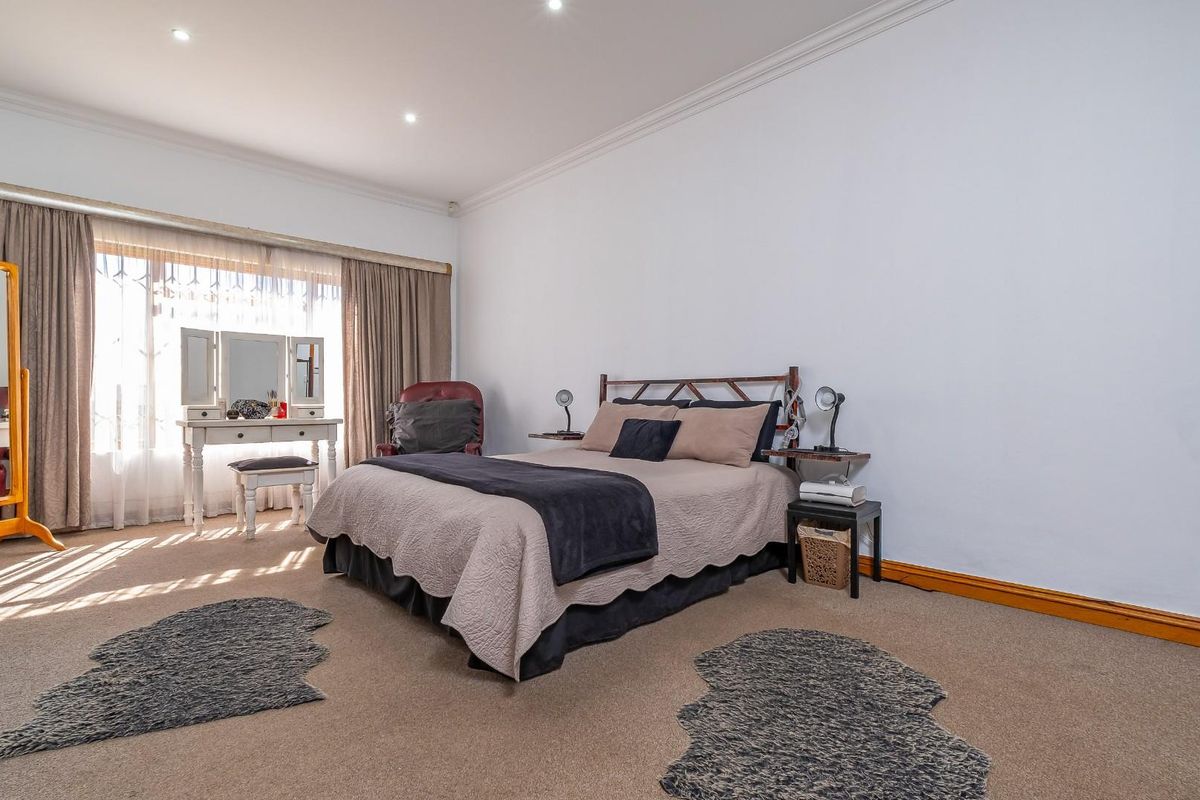 A spacious bedroom featuring neutral carpeting, recessed downlighting, and classic cove cornicing, offering a comfortable and well-lit living space.