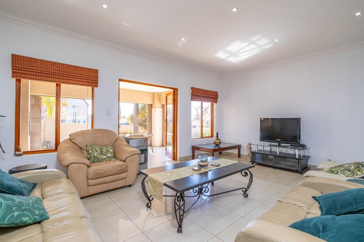 Spacious living room featuring tiled flooring, recessed downlighting, and direct access to an outdoor patio area through sliding doors.
