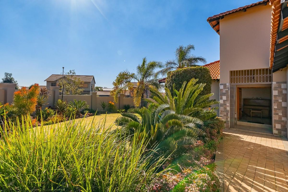 A well-maintained rear garden featuring a paved walkway, established landscaping, and a secure perimeter wall, providing a private outdoor space.