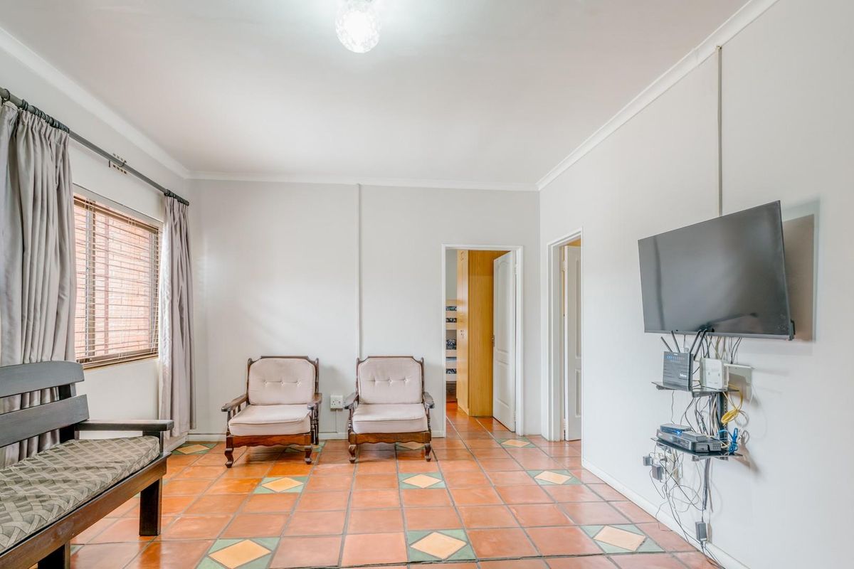 A living room featuring terracotta tiled flooring, cove cornicing, and access to adjacent rooms.