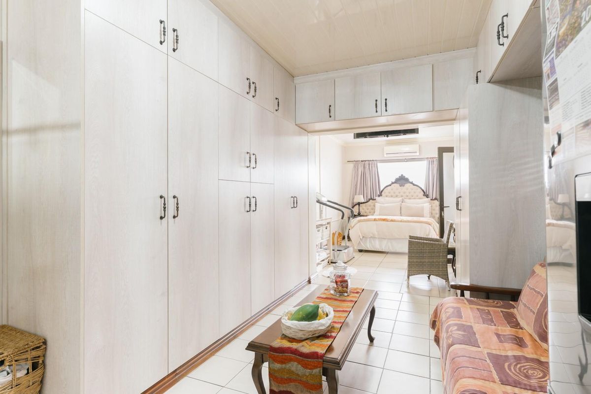 Spacious bedroom featuring extensive built-in cabinetry, overhead storage, tiled flooring, and an integrated air conditioning unit.