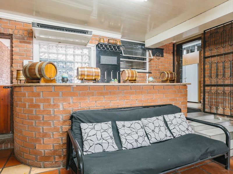 A rustic indoor bar area featuring a brick counter, tiled flooring, and a split system air conditioner, providing a cozy space for entertaining.