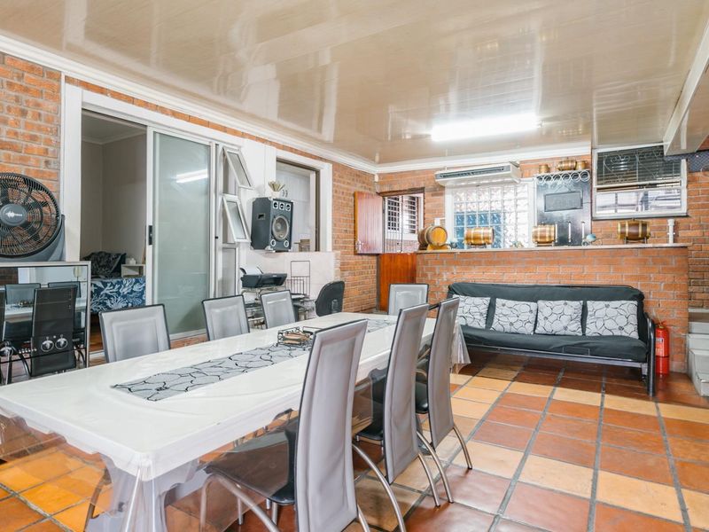 Spacious open-plan living and dining area featuring exposed brick walls, terracotta tiling, and a built-in brick breakfast bar.