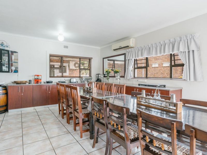 Spacious dining area featuring extensive built-in cabinetry with granite countertops, tiled flooring, and a wall-mounted air conditioning unit.