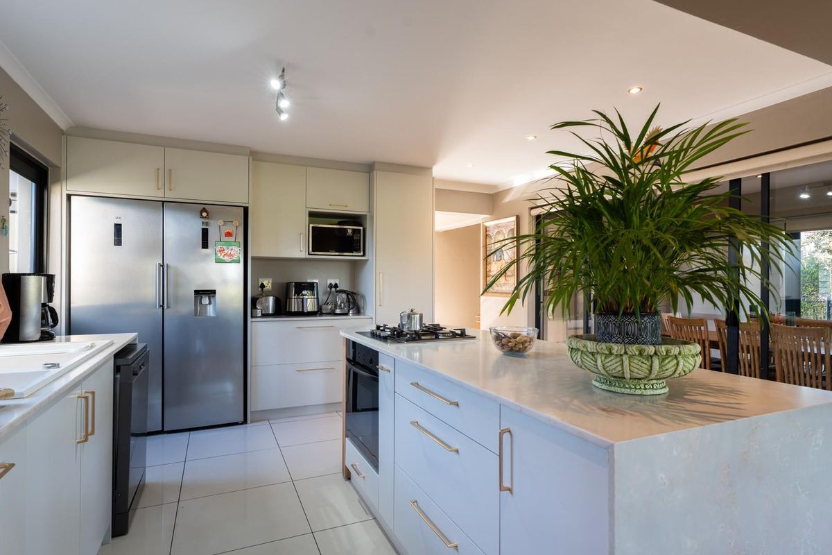 Modern kitchen featuring a central island, built-in oven, gas hob, and ample cabinetry, seamlessly flowing into the adjacent dining area.