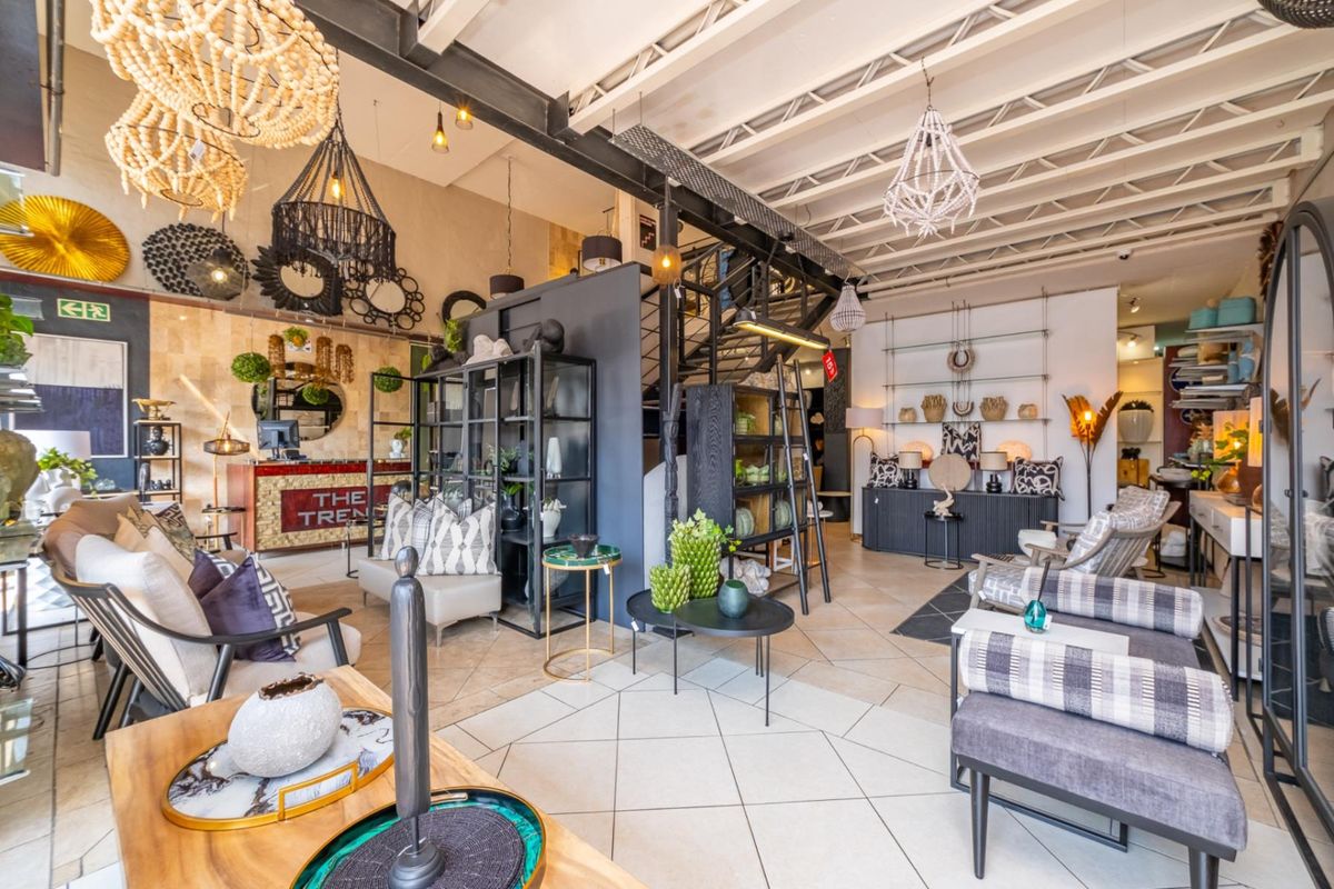 Spacious open-plan retail showroom featuring exposed industrial steel beams, high ceilings with exposed trusses, and tiled flooring throughout.