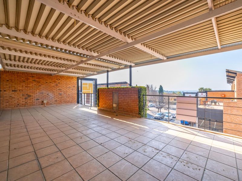 Spacious covered balcony featuring exposed brick walls, tiled flooring, and metal railings, offering an open-air area suitable for outdoor seating or commercial use.