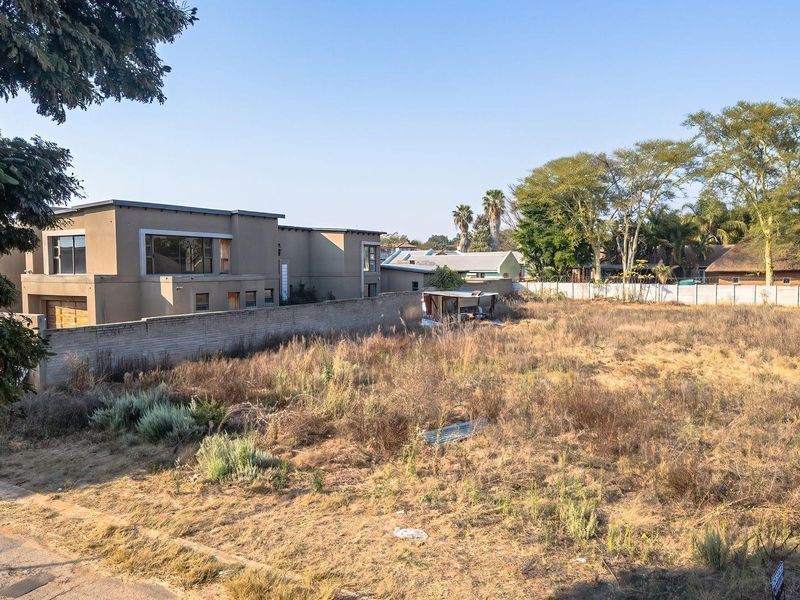A vacant residential plot of land featuring a boundary wall, situated in a developed neighborhood.