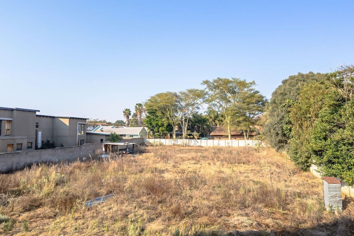 A vacant residential plot featuring perimeter walling and established trees, offering a blank canvas for future development.