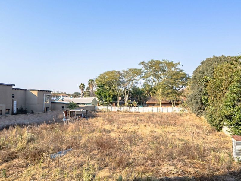 A vacant residential plot featuring perimeter walling and established trees, offering a blank canvas for future development.