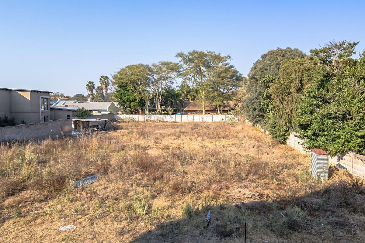A vacant residential plot featuring perimeter walling, established trees, and open land, offering a blank canvas for future development.