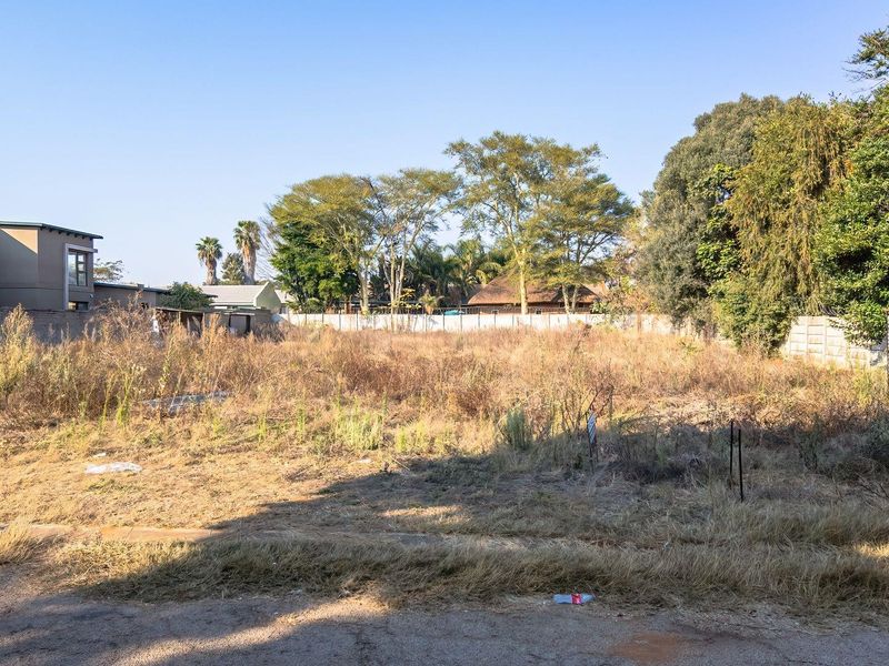 A vacant residential plot featuring perimeter walling and a small metal storage structure, ready for development.