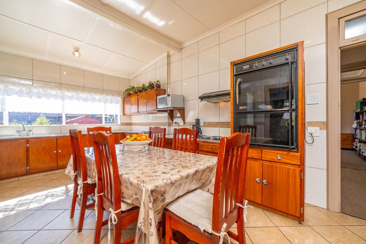 A functional kitchen featuring built-in wooden cabinetry, an eye-level oven, extractor fan, and tiled finishes throughout, offering a classic layout with ample storage space.