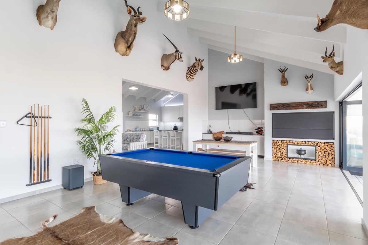 Spacious living area featuring a vaulted ceiling, tiled floors, and a built-in fireplace, with an open-plan flow into the adjacent kitchen.