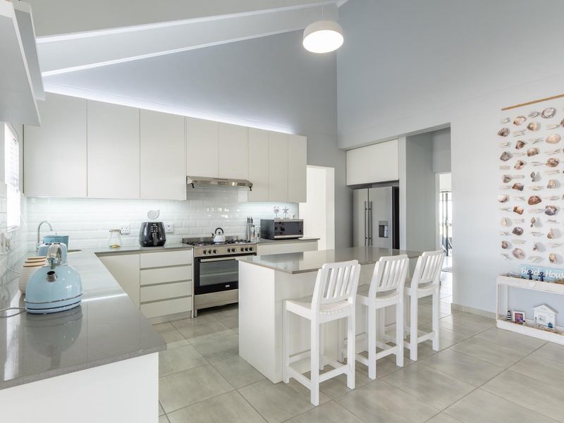 Modern kitchen featuring white cabinetry, quartz countertops, subway tile backsplash, a central island, and a high vaulted ceiling with integrated lighting.