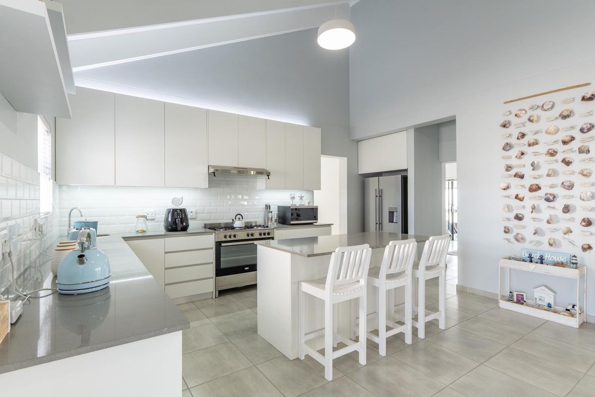 Modern kitchen featuring white cabinetry, quartz countertops, subway tile backsplash, a central island, and a high vaulted ceiling with integrated lighting.
