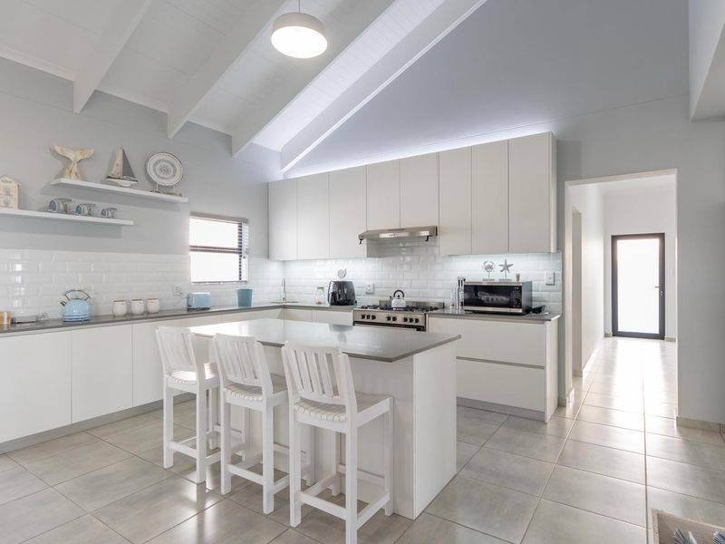 Modern, bright kitchen featuring a central island, subway tile backsplash, gas stove, and vaulted ceilings with clean, contemporary cabinetry.