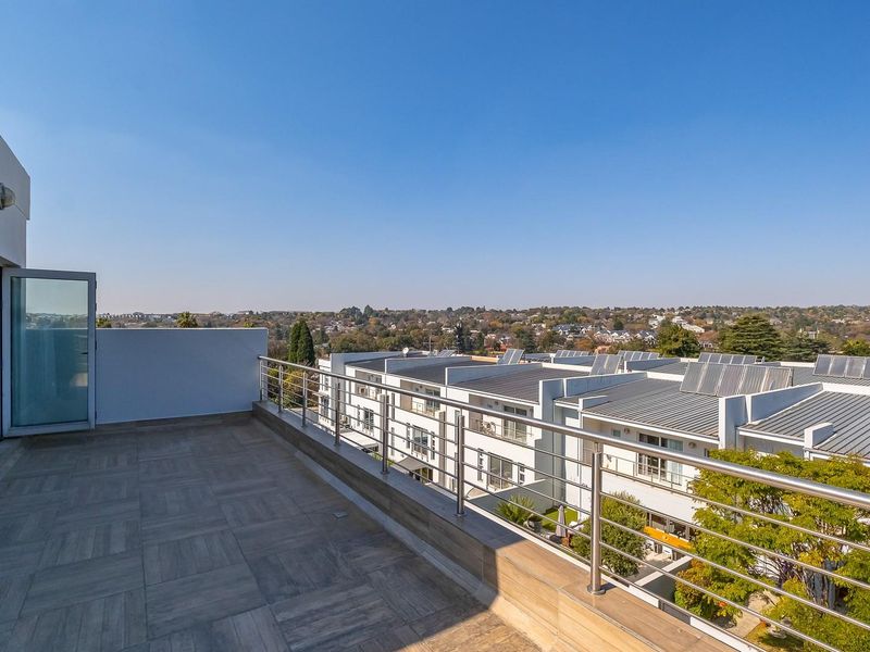 Spacious balcony featuring modern tiled flooring and a stainless steel balustrade, offering expansive elevated views over the surrounding residential estate.
