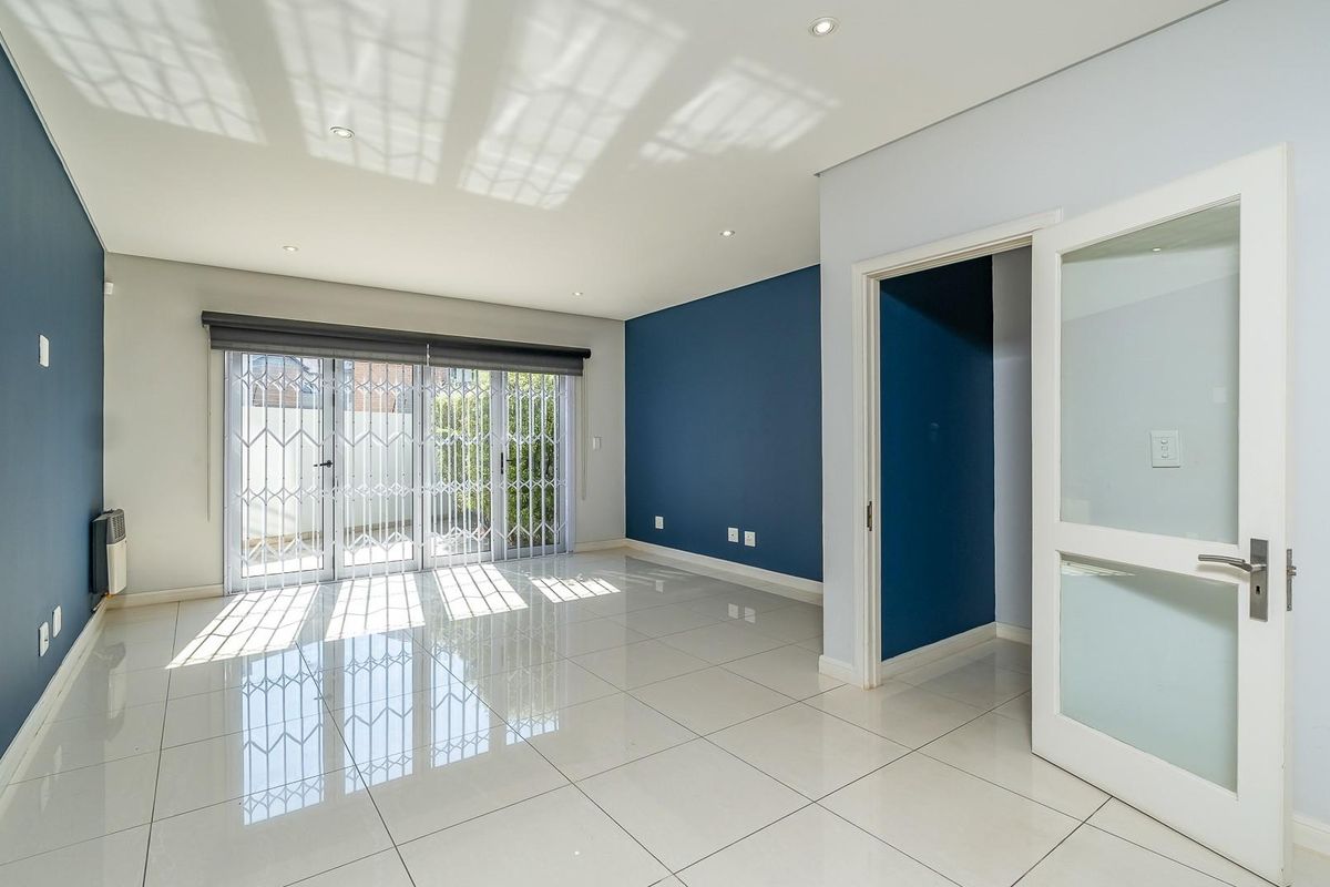 Spacious, light-filled living area featuring polished porcelain tile flooring, recessed lighting, and sliding glass doors leading to an outdoor space.