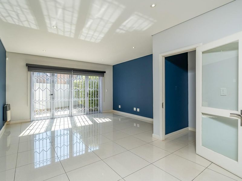 Spacious, light-filled living area featuring polished porcelain tile flooring, recessed lighting, and sliding glass doors leading to an outdoor space.