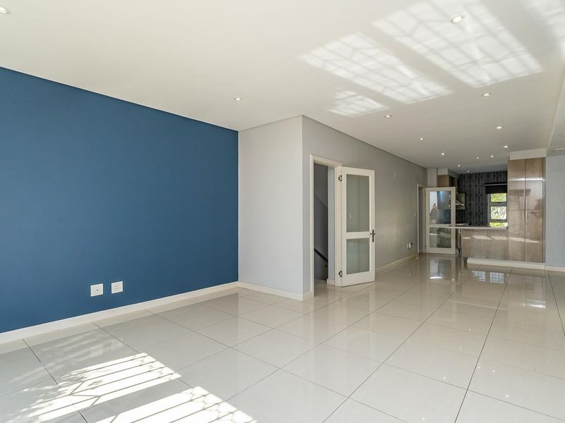 Spacious open-plan living area featuring polished porcelain tiles, recessed lighting, and a modern kitchen with integrated cabinetry and a central island.