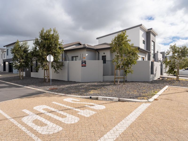 Modern residential property exterior featuring a clean facade, perimeter wall with electric fencing, and paved driveway access from the street.