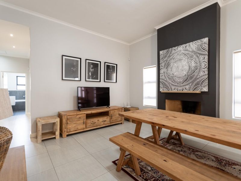 A well-maintained living area featuring a prominent fireplace with a dark feature wall, neutral tiled flooring, and recessed lighting.