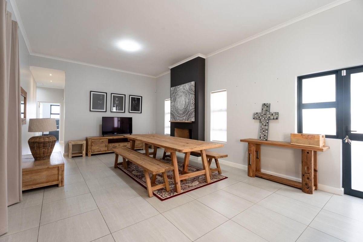 Spacious living area featuring neutral tiled flooring, a central fireplace with a dark feature wall, and large windows providing ample natural light.