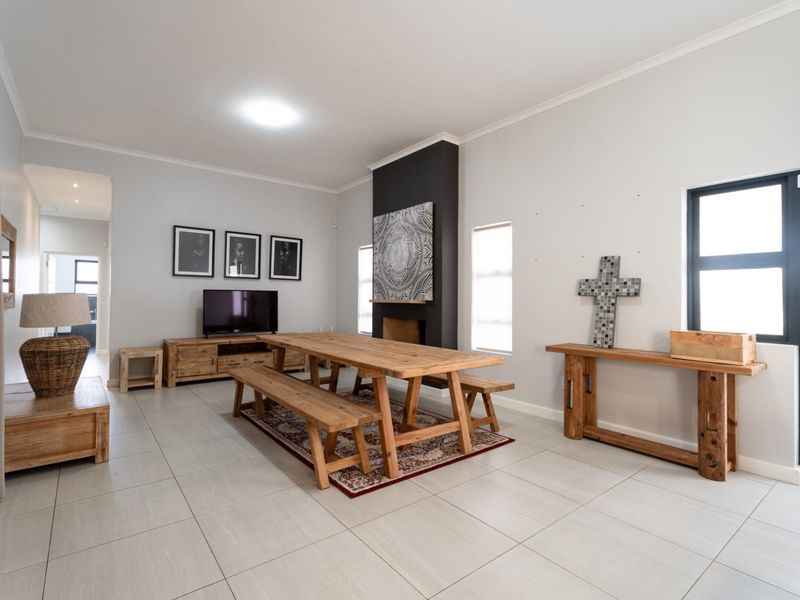 Spacious living area featuring neutral tiled flooring, a central fireplace with a dark feature wall, and large windows providing ample natural light.