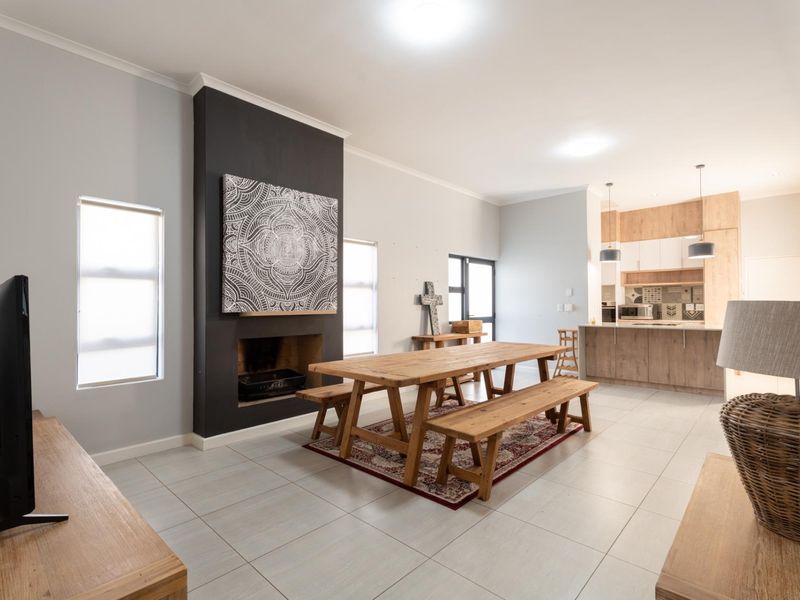 Spacious open-plan living and dining area featuring a modern kitchen with island, tiled floors, and a striking black feature fireplace.