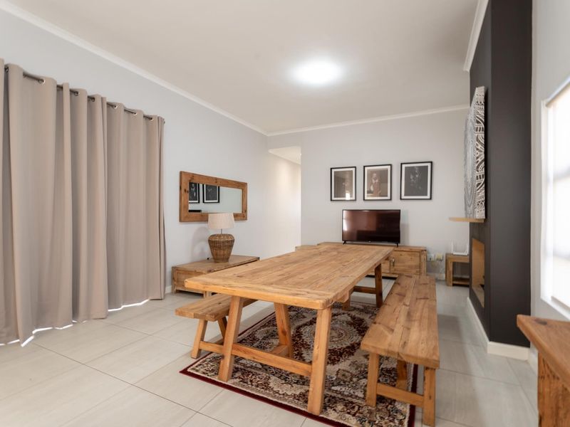 A bright living area featuring tiled flooring and a modern fireplace, offering a versatile space for relaxation and dining.
