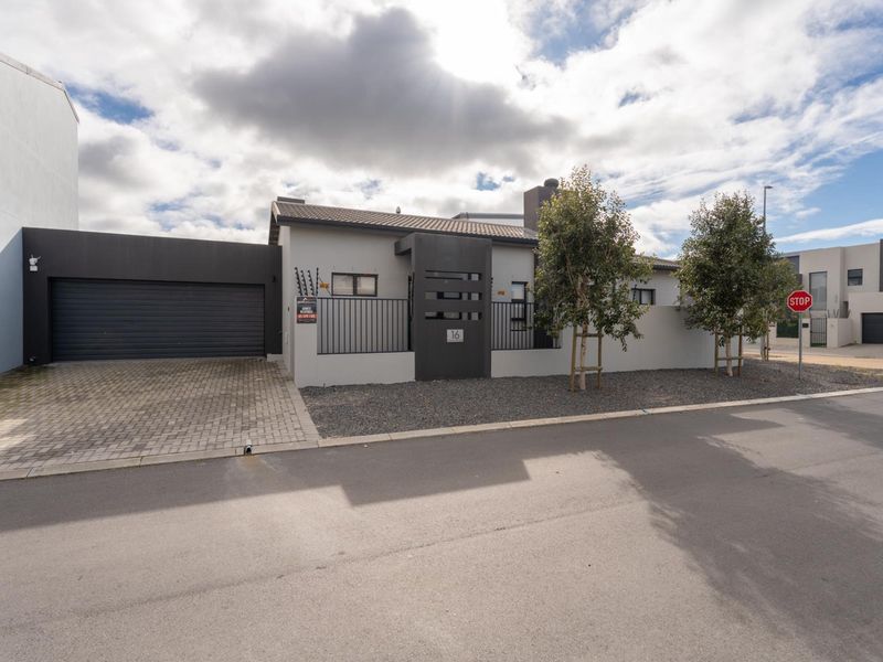 Modern front elevation of a residential property featuring a paved driveway, double garage, and secure perimeter wall with electric fencing.