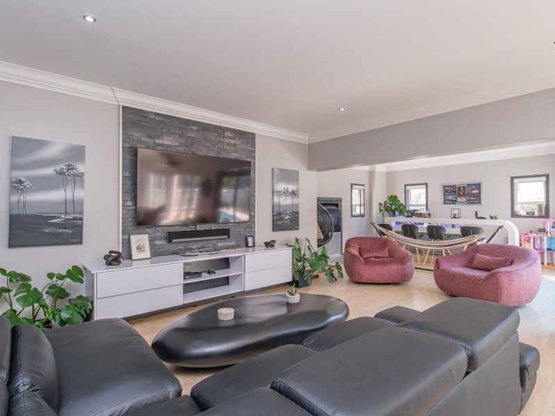 Spacious open-plan living area featuring a stone-clad media wall, recessed lighting, and a dedicated bar area with modern finishes.