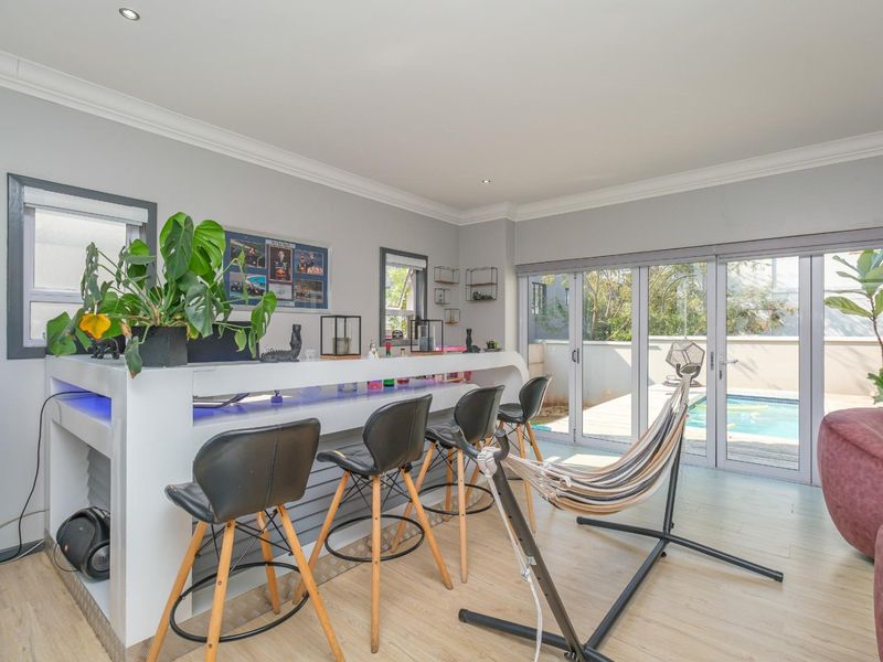 A modern entertainment bar area featuring a built-in counter with integrated LED lighting and large aluminium stacker doors opening to the pool deck.
