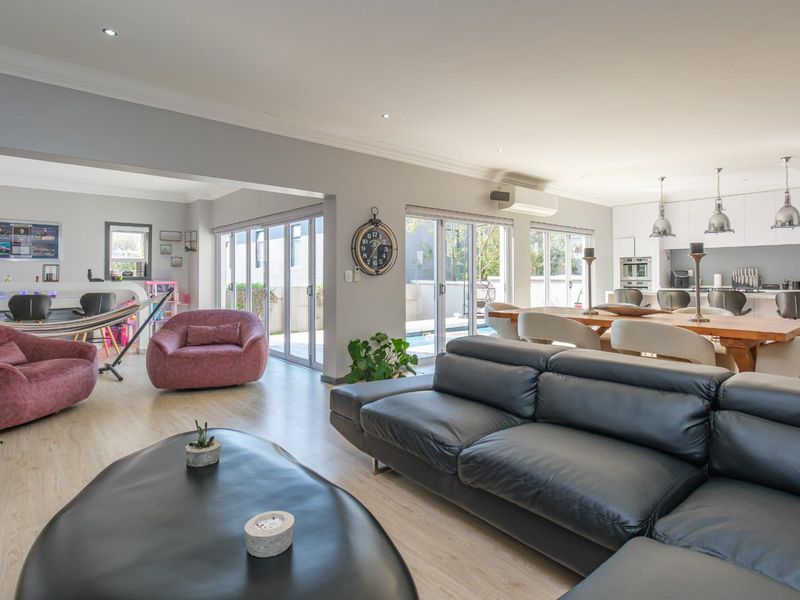 Spacious open-plan living and dining area featuring modern kitchen with island, recessed lighting, and large sliding doors opening to the outdoor pool area.