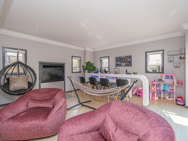 Open plan living area featuring a built-in fireplace, breakfast bar, recessed downlights, and light-toned laminate flooring.