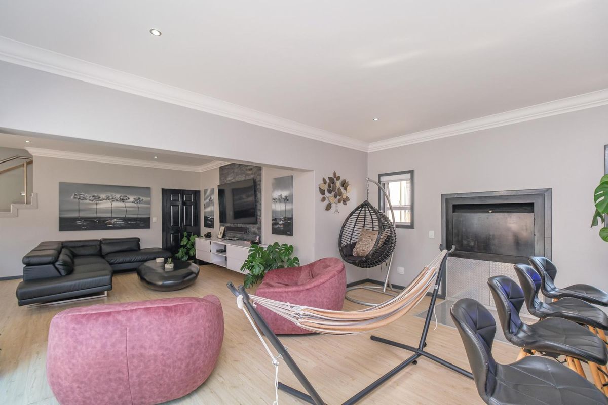 Spacious living area featuring a stone-clad fireplace, recessed downlighting, and light-toned laminate flooring, creating a modern and comfortable atmosphere.